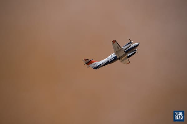 A US Forest Service air attack plane flies over a wildfire to coordinate air resources.