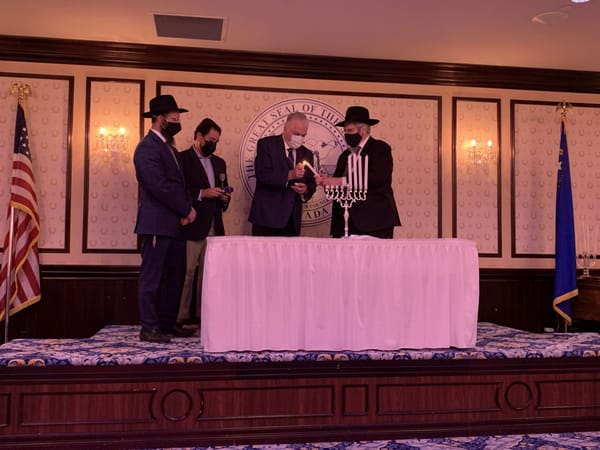 Gov. Steve Sisolak lights the candle on the menorah for the fourth night of Hanukkah with members of Nevada's Jewish communit